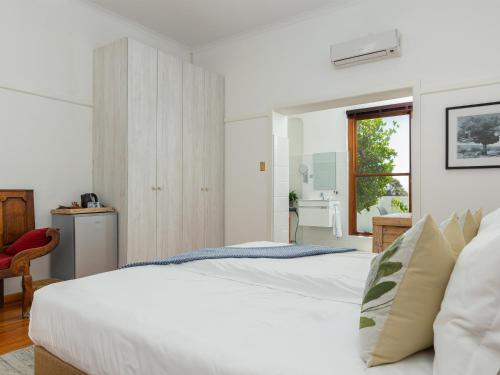 a white bedroom with two beds and a window at Abbotts Hill in Malmesbury