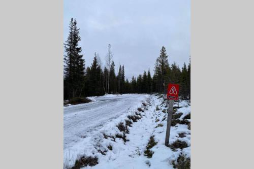 a snow covered road with a sign on it at Northernlight cabin in Kiruna