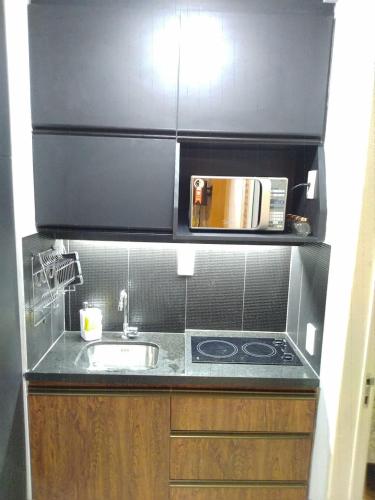 a small kitchen with a sink and a microwave at Flat Beach Class Resort Muro Alto in Porto De Galinhas