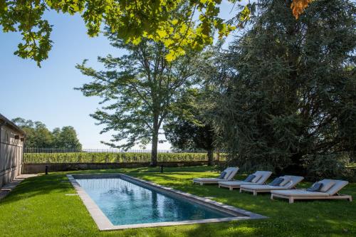 a yard with a swimming pool with lounge chairs next to at Château Malescasse in Lamarque