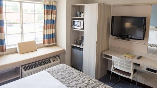 a small room with a tv and a desk with a window at Microtel Inn & Suites - Greenville in Greenville