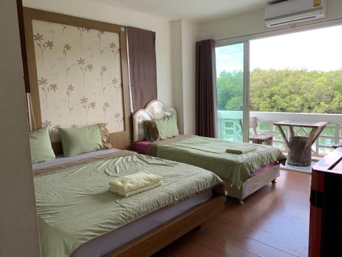 two beds in a room with a balcony at Banchaitalay Room in Rayong