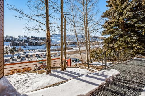 a snow covered sidewalk with a fence and trees at Butte Basecamp in Crested Butte