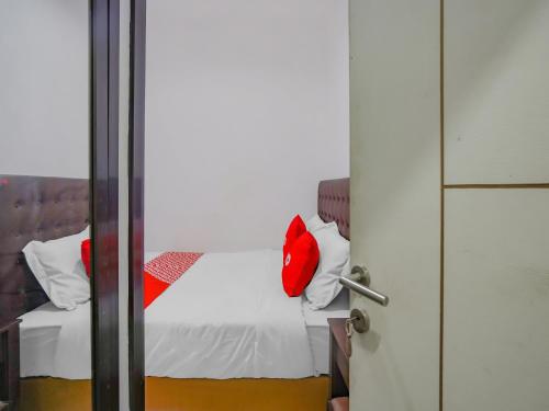 1 dormitorio con cama blanca y almohadas rojas en SPOT ON 90110 A1 Pakis Argosari, en Surabaya
