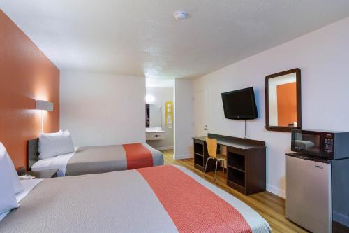 a hotel room with two beds and a desk and a television at Studio 6 Gainesville, Fl in Gainesville