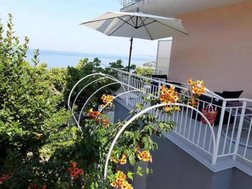 a balcony with an umbrella and some flowers at Apartmani Vesna Miliša in Primošten