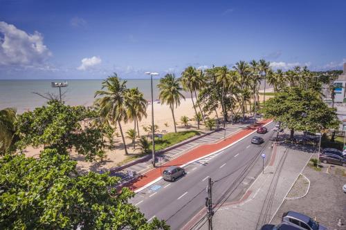 a street with palm trees and a road next to the beach at Luxor Cabo Branco Home Service in João Pessoa