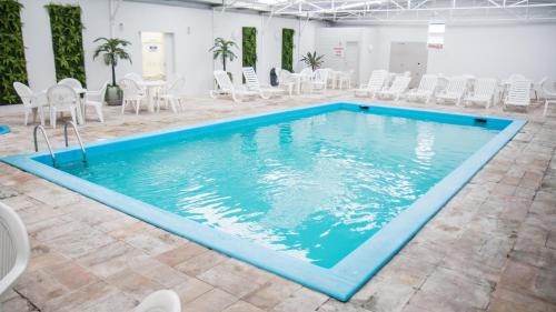 una gran piscina con sillas blancas, mesas y sillas en San Marino Cassino Hotel, en Balneário Camboriú