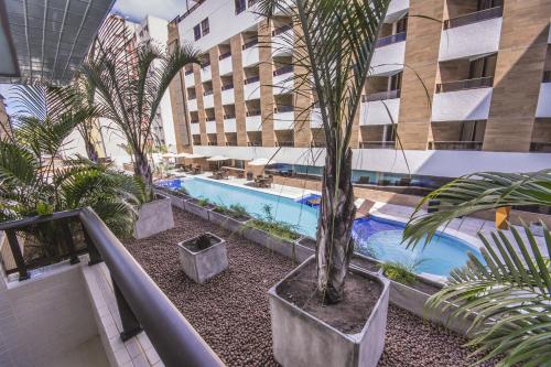 a building with a swimming pool and palm trees in it at GOLDFLAT Cabo Branco by PenareiaTurBr in João Pessoa