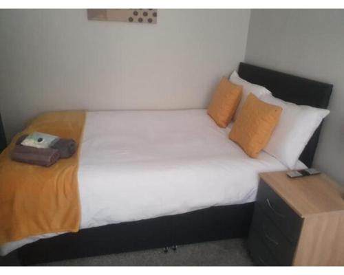 a bedroom with a bed with white sheets and orange pillows at Townhouse @ Nicholls Street Stoke in Stoke on Trent