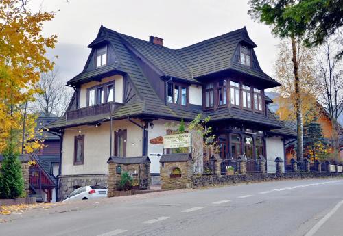 uma grande casa a preto e branco ao lado de uma rua em Czarna Willa em Zakopane
