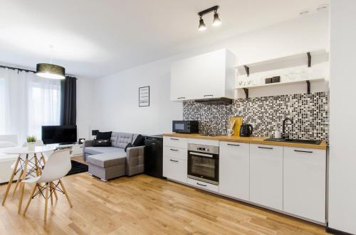 a kitchen with white cabinets and a living room at GoldAparts Centrum in Łódź