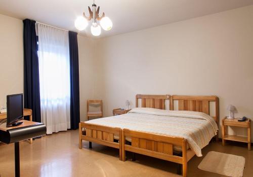 een slaapkamer met een bed en een flatscreen-tv bij Albergo Michielini in Spilimbergo