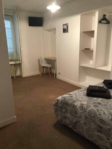 een slaapkamer met een bed, een bureau en een stoel bij Hotel le faubourg in La Guerche-de-Bretagne