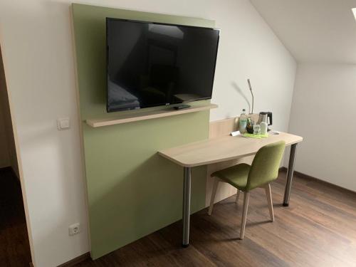 a room with a table and a television on a wall at Marias Inn - Bed & Breakfast in Garching bei München