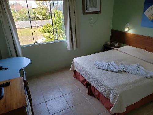 a bedroom with a bed and a window at De Rose Praia Hotel in Torres