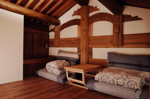 Habitación con 2 camas y una silla. en 新龍頭古厝本館 Shin Long Tou B&B en Jinning