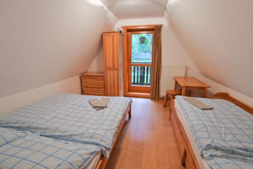 a attic bedroom with two beds and a window at Drevenica pod Lánom in Zuberec