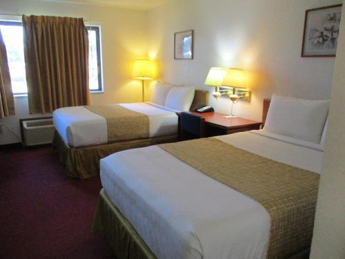 a hotel room with two beds and a table with lamps at Travelodge by Wyndham Redwood Falls in Redwood Falls