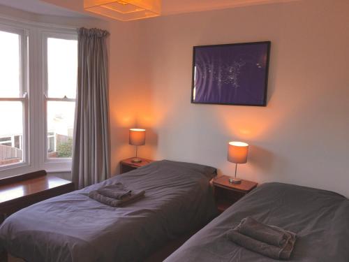 two beds in a room with two lamps and a window at Park View - Two bedroom apartment in Worthing