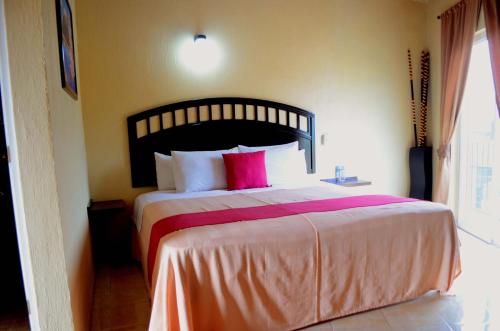 a bedroom with a large bed with a red pillow at Hotel Gesa in Villa Corona