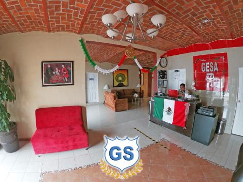 a living room with a red chair and a counter at Hotel Gesa in Villa Corona