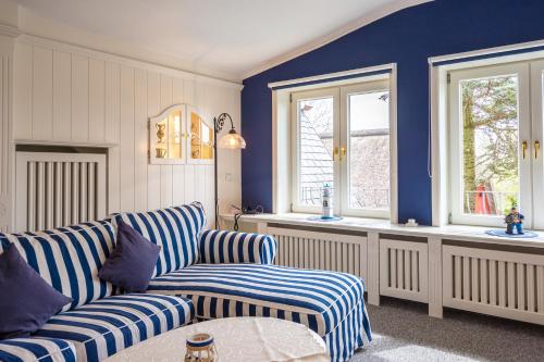 a living room with a couch and two windows at Inselhotel Arfsten in Wyk auf Föhr