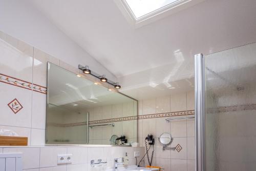 a bathroom with a large mirror and a shower at Inselhotel Arfsten in Wyk auf Föhr