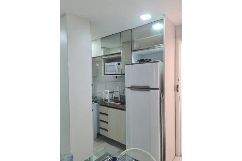 a kitchen with white cabinets and a refrigerator at Porto de Galinhas | Muro Alto 116B in Porto De Galinhas