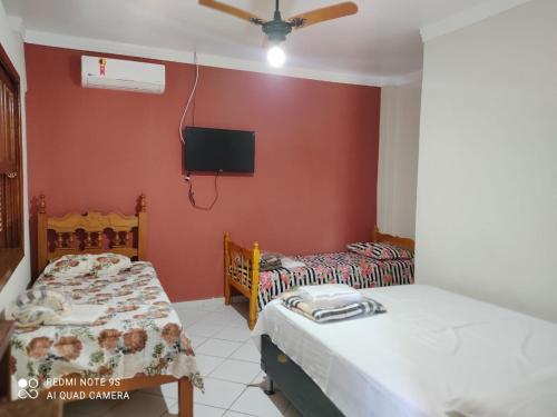 2 Betten in einem Zimmer mit einem TV an der Wand in der Unterkunft Villa Franco in Águas de São Pedro