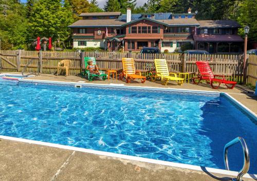 a swimming pool with chairs and a house in the background at Kitzhof Inn Vermont in West Dover