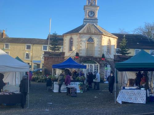 a market in front of a building with a clock tower at Brampton Holiday Homes - Beckside Apartment in Brampton