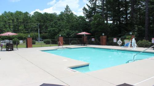 uma grande piscina azul com mesas e guarda-sóis em Holiday Inn Express Hotels & Suites Rockingham West, an IHG Hotel em Rockingham