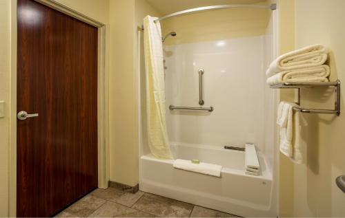 a bathroom with a tub and a shower with towels at Cobblestone Inn & Suites - Brookville in Brookville
