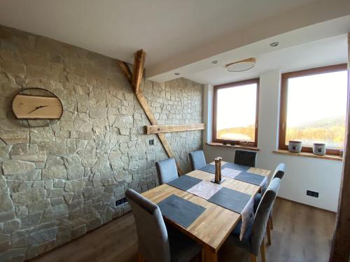 a dining room with a stone wall and a wooden table and chairs at Chalet Apartments Maštal in Železná Ruda
