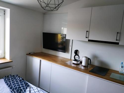 a kitchen with white cabinets and a television on a counter at theApartments Manufaktura in Łódź