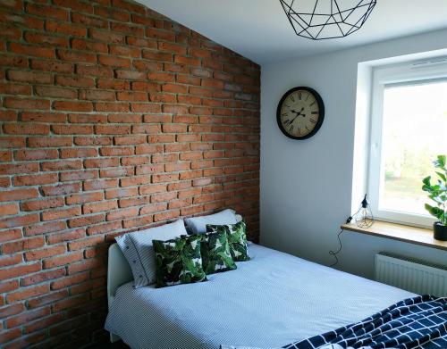 sypialnia z ceglaną ścianą i łóżkiem z poduszkami w obiekcie theApartments Manufaktura w Łodzi