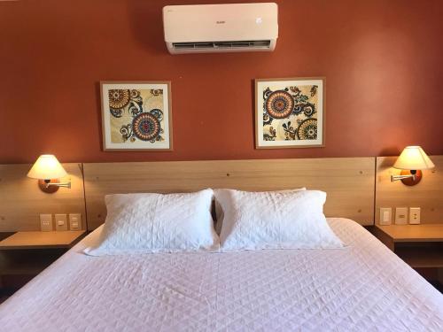 een slaapkamer met een groot wit bed met 2 lampen bij Manacá Apartamentos , Kariri Beach , Cumbuco in Cumbuco