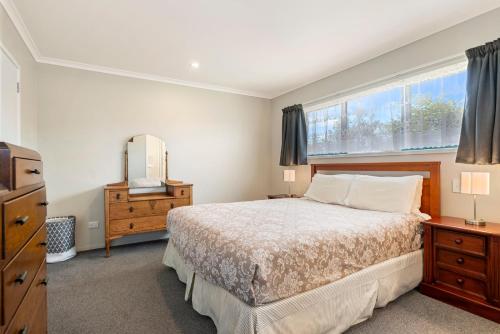 a bedroom with a large bed and a window at Sunrise Getaway - Rotorua Holiday Home in Ohinemutu