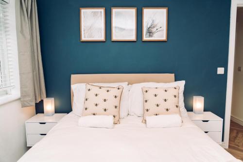 a blue bedroom with a white bed with pillows at Caroline Court - 1 Bedroom Apartment in Colchester