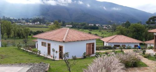 une maison blanche avec une montagne en arrière-plan dans l'établissement Ocarina Suites, à Villa de Leyva