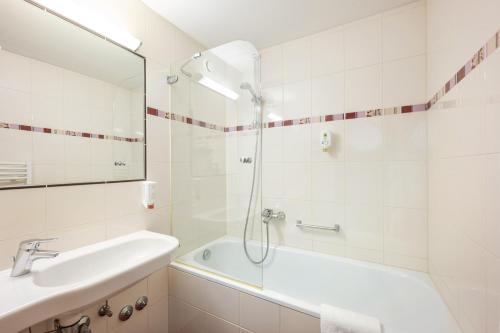 a bathroom with a shower and a tub and a sink at Hotel Appartement Winter in Obertauern