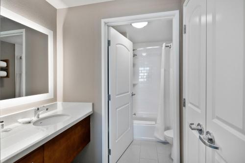 a white bathroom with a sink and a shower at Staybridge Suites Irvine - John Wayne Airport by IHG in Irvine