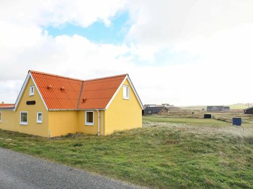 a yellow house with a red roof on the side of a road at 6 person holiday home in Lemvig in Ferring