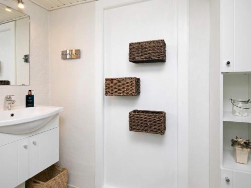 a bathroom with a sink and wicker baskets on the wall at Holiday home Assens VI in Assens