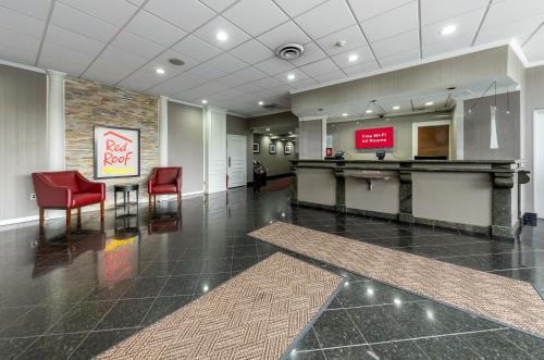 an empty lobby with a table and red chairs at Red Roof PLUS Newark Liberty Airport - Carteret in Carteret