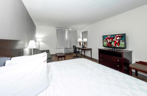 a bedroom with a bed and a flat screen tv at Red Roof PLUS Newark Liberty Airport - Carteret in Carteret