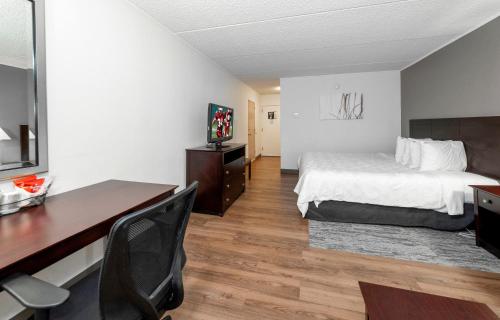a hotel room with a bed and a desk and a desk at Red Roof Inn PLUS Newark Liberty Airport - Carteret in Carteret