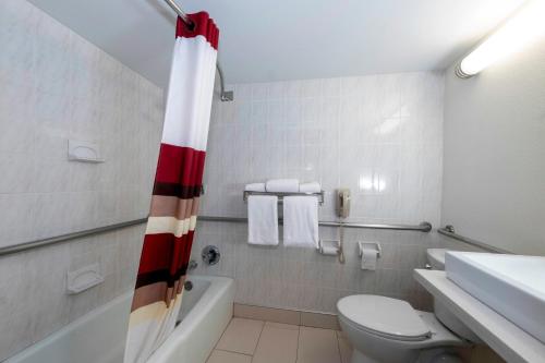 a bathroom with a red and white shower curtain at Red Roof PLUS Newark Liberty Airport - Carteret in Carteret