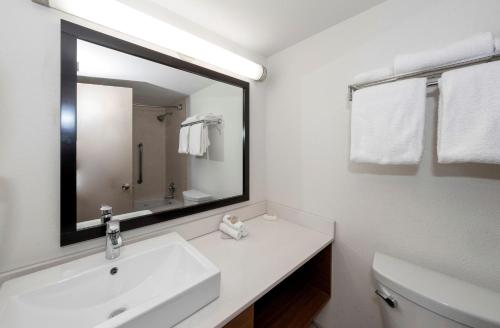 a white bathroom with a sink and a mirror at Red Roof PLUS Newark Liberty Airport - Carteret in Carteret